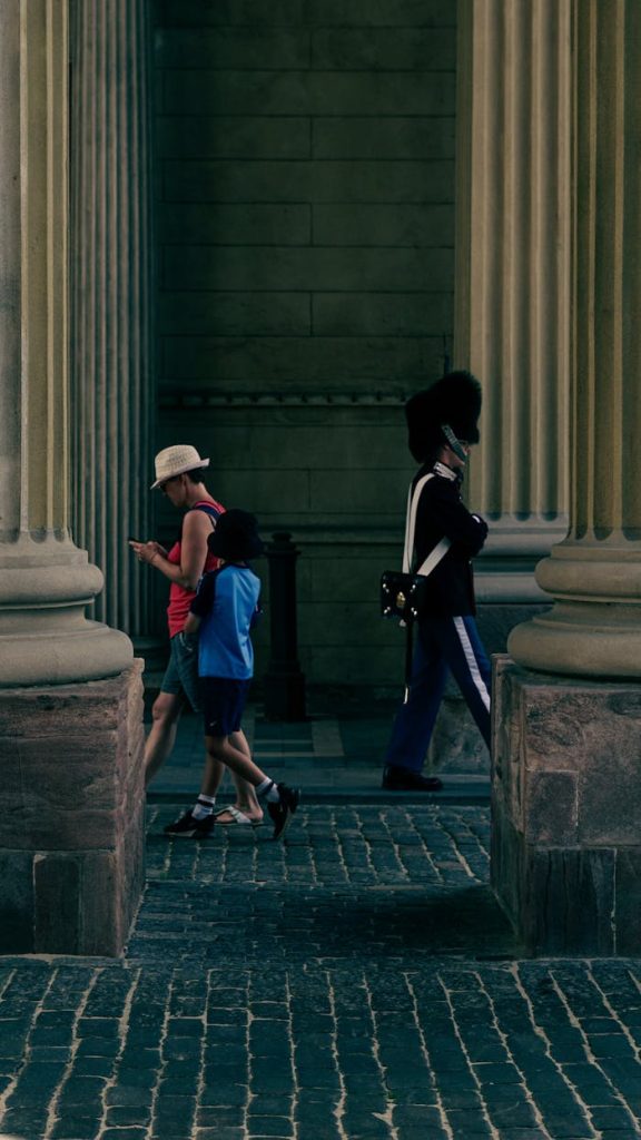 Tourists walking past a Royal Guard at Amalienborg Palace in Copenhagen.